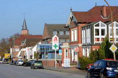 Unterschiedliche Architekturformen, Einzelhäuser mit Geschäften - Kieler Strasse in Quickborn; im Hintergrund der Kirchturm der Marienkirche.
