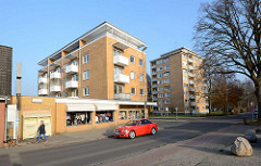 Mehrstöckige Wohnblocks mit gelber Ziegelfassade / Balkons - flache Ladengeschäfte; Harksheider Weg / Quickborn.
