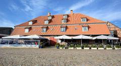 Hornscher Speicher - historische Architektur am Hafen von Neustadt in Holstein - Restaurant mit Sonnenschirmen, Kopfsteinpflaster.