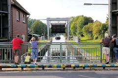 Schleuse in Mirow - Teil der Müritz Havel Wasserstrasse; technisches Denkmal / Höhenunterschied von 3,50m. Passanten beobachten von der Strassebrücke den Schleusenvorgang - ein Sportboot fährt in die Schleusenkammer ein.