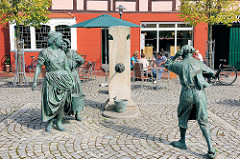 Fiek'n Brunnen vor dem Rathaus von Hagenow, Rathausplatz / Lange Strasse. Der Brunnen 2007 errichtet, Künstler Bernd Streiter - ein Schusterjunge belauscht zwei Frauen beim Tratschen.