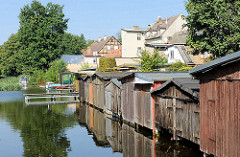 Bootshäuser aus Holz am Ufer der Gänsehavel in Fürstenberg - im Hintergrund Wohnhäuser an der Havelstrasse.