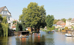Kanus in der Gänsehavel von Fürstenberg; Wohnhäuser und Bootshäuser am Ufer des Nebenarms der Havel.