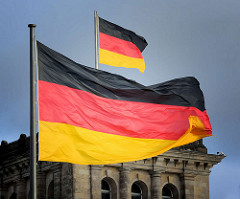 Flagge der Bundesrepublik Deutschland / Bundesflagge - deutsches Hoheitszeichen / Staatssymbol; wehen im Wind beim Reichstagsgebäude in Berlin.