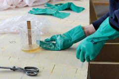 Laminierungsarbeiten beim Bootsbau - zum Schutz gegen das Epoxidharz werden Gummihandschuhe getragen.