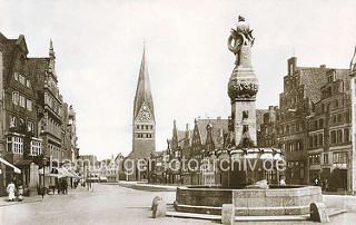 Historische Aufnahme vom Lüneburger Platz AM SANDE; im Vordergrund der Reichenbachbrunnen mit Tränken - im Hintergrund die St. Johanniskirche. Der Platz ist von historischen Giebelhäusern gesäumt.