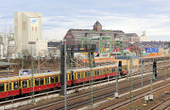 Einfahrender S-Bahnzug in der Haltestelle Beusselstrasse - im Hintergrund Industriearchitektur im Berliner Westhafen.
