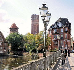 Blick von der Altenbrückertorstrasse in Lüneburg über die Ilmenau; Kandelaber / Laternen auf der Brücke - lks. der Wasserturm und die Ratsmühle.