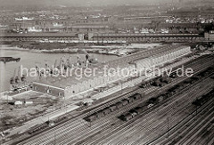 Luftfoto vom Windhukkai des Süd - West - Hafens,  dem Lagerschuppen 59  mit den Tonnengewölben am Veddeler Damm und den Gleisanlagen des Güterbahnhofs Hamburg Süd - der Togo Kai ist noch nicht befestigt. Dahinter stehen Güterwaggons auf den Gleis