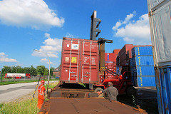 Der Schwerlaststabler senkt den Container auf den Güterzug.