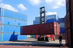 Ein Schwerlaststabler / Gabelstabler transportiert einen Container vom Containerlager zum Güterzug.