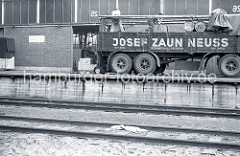 Der Gabelstaplerfahrer hat die Fässer auf der Ladefläche des LKW-Anhängers abgeladen - zwei Arbeiter rollen die Metalltonnen auf dem Anhänger der Spedition Josef Zaun / Neuss, um sie sicher zu verstauen.