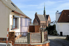 Einzelhaus mit Windfang - Baustil der 1960er Jahre; im Hintergrund die St. Bonifatius-Kirche in Bergen auf Rügen.