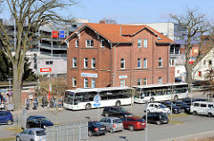 Bushaltestelle, Autobusse beim Bahnhof Buchholz i.d.N., parkende Autos.