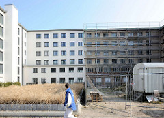 Neu + Alt; teilweise saniertes Gebäude, weisse Hausfassade - eingerüstete Fassade im Rauhputz.