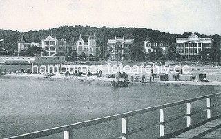 Historische Ansicht - Blick von der Seebrücke auf das Ostseeufer bei Binz; Segelboot und Standkörbe am Sandstrand - Villen in Bäderarchitektur.