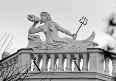 Skulptur / Stuckelement an einer Balkonbrüstung mit Säule; nackte Nixe mit Schwimmflosse, Dreizack und Muschel.  Bäderarchitektur an der deutschen Ostsee - Architeturfotos aus Binz auf Rügen.