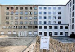 Neu + Alt; teilweise saniertes Gebäude, weisse Hausfassade - leerstehendes Gebäude, Fensterhöhlen - Fassade mit grauem Putz. Schild Privatgelände, Betreten nur für Anlieger.