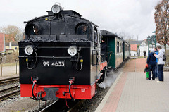 Der Zug der Rügenschen Kleinbahn kommt von Putbus und fährt in den Bahnhof Binz ein - gezogen von der Dampflokomotive 99 4633.