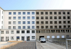 Neu + Alt; teilweise saniertes Gebäude, weisse Hausfassade - leerstehendes Gebäude, Fensterhöhlen - Fassade mit grauem Putz.