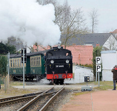 Der Zug der Rügenschen Kleinbahn kommt von Putbus und fährt in den Bahnhof Binz ein - gezogen von der Dampflokomotive 99 4633.