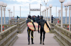 Seebrücke Binz - Surfer mit Surfbrett gehen zum Surfen im 4 Grad warmen Ostseewasser - Frühling an der Ostseeküste.