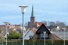 Laternen / Lampen auf einem Parkplatz in Bergen - im Hintergrund der Kirchturm der St. Marien-Kirche in Bergen auf Rügen.