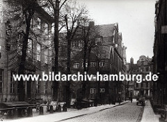 der alte Wandrahm im Gebiet der der zukünftigen Hamburger Speicherstadt - die Strasse ist mit Kopfstein gepflastert, ein Pferdewagen mit Kisten beladen steht am Strassenrand. Leere Karren / Schottsche Karren sind auf einem Hof abgestellt.