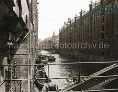 Blick von der Kehrwiederstegbrücke auf das Brooksfleet; Schuten und Barkassen liegen an der Gebäudemauer des Speichergebäudes Block D. Die Kaffeeladung eines der Kähne wird gerade gelöscht.