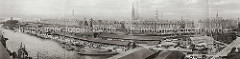 Historisches Panorama vom Grasbrookhafen; Binnenschiffe und Schuten liegen am Dalmannkai vor den offenene Lagerschuppen, in denen die Waren gestapelt sind. Auf der Landseite stehen auf den Schienen der Hafenbahn die Güterwaggons mit denen die War