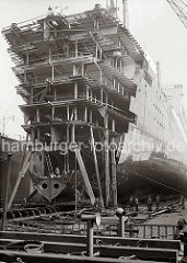 An einem Passagierschiff der HAPAG Reederei wird im Schwimmdock der Werft Bohm & Voss gearbeitet - u.a. wurde 1933/34 der Turbinen-Schnelldampfer  Deutschland (IV) von 183m auf 197m auf der Hamburger Werft verlängert.