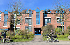 Moderne Wohnblocks mit Dachwohnungen - blau abgesetzte Fensterelemente - RadfahrerInnen in der Austrasse von Wedel.