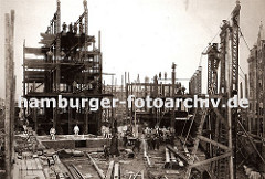 die Eisenträger des Speicherblock H werden hoch gezogen - Bauarbeiter balancieren auf dem Gerüst; einfach zusammen genagelte Holzleitern werden zum Besteigen der Hamburger Grossbaustelle benutzt.