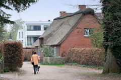 Reetgedecktes Wohnhaus in Wedel, dahinter ein Neubau.