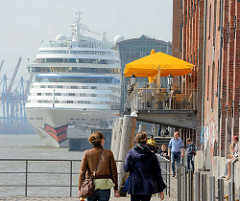 Uferpromenade an der Elbe in Hamburg Altona - Restaurant mit Sonnenschirmen am Wasser - Kreuzfahrtschiff am Altonaer Terminal.