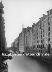 Blick über den Brooksfleet Richtung Elbe und dem Hamburger Hafen. Die Schuten liegen auf dem Wasser - das Boot im Vordergrund ist mit Ballen beladen. Die Sonne wirft die Schatten der Giebel an die Speicherwand.