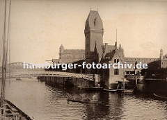 zwei Männer staken ihren Kahn mit langen Stangen über den Zollkanal in Höhe der Fussgängerbrücke Jungfernbrücke - im Hintergrund ist der Bogen der Kornhausbrücke zu erkennen. Auf dem kleinen Schiffsanleger am Kai des Kanals werden in einer hölzer