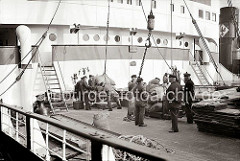 An Deck des Frachters im Hamburger Hafen bereiten die Hafenarbeiter das Löschen einer Ladung Säcke vor. Die Hieve Sackgut wird auf einer mobilen Wage gewogen, um dann mit dem Kran an Land gebracht zu werden; ca. 1934.