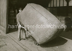Der grosse Ballen wird vom Lagerarbeiter auf einer Sackkarre von der Laderampe aufgenommen und in das Innere des Lagerschuppens transportiert. ( ca. 1930 )