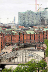 Blick zum Zollkanal und Speichergebäuden der Speicherstadt - im Vordergrund die Brooksbrücke, dahinter die Kibbelstegbrücke - alles wird überragt von der entstehenden Elbphilharmonie.