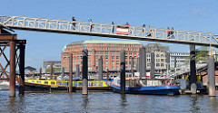 Blick vom Zollkanal zum Hamburger Binnenhafen - Barkassen liegen im Wasser; Touristen auf der Fussgängerbrücke / Kehrwiedersteg.
