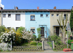 Einstöckige Reihenhäuser mit unterschiedlich farblich abgesetzer Fassade / Gartenzaun; Imbekstieg in Hamburg Stellingen.