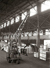 Arbeitserleichterung durch den Einsatz von Maschinen im Hafen Hamburgs: in einem Lagerschuppen fährt der Fahrer einen Papierballengreifer durch den Gang zu seinem Arbeitseinsatz; ca. 1932.