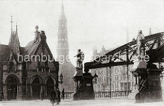 Die Skulpturen der Entdecker Ferdinand Magellan (lks.) und James Cook stehen auf der Freihafenseite der Kornhausbrücke. Zollbeamte mit Dienstmütze und langen Mänteln befinden sich vor dem Zollgebäude an der Zollgrenze des Freihafengeländes. Im