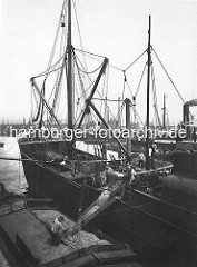 Hansahafen - Dampfer beim Kornlöschen im Hamburger Hafen; ein Arbeiter verteilt das Korn mit der Schaufel auf der Schute.