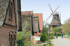 Wohnhäuser und Windmühle / Borsteler Mühle in  Jork, Altes Land - Radfahrer.