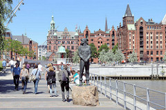 Störtebeker Denkmal am Magdeburger Hafen in der Hamburger Hafencity - im Hintergrund Backsteinarchitektur. Spaziergänger in der Sonne am StörtebekerUfer.