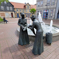 Bronzeskulpturen am Marktbrunnen vor dem Alten Rathaus in Lüchow - zwei weibliche Bronzeskulpturen / Leinenweberinnen; eine Altbäuerin prüft das Leinen ihrer Tochter. Mitte des 19. Jahrhunderts wurden in Lüchow ca. 1 Mio. Meter Leinen gewebt und wurd