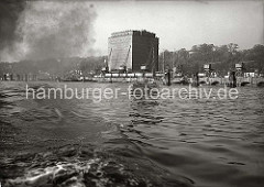 Blick vom fahrenden Schiff über die Elbe zum UNION KÜHLHAUS in Neumühlen / Altona. Ein Frachtsegler liegt am Kai, eine Barkasse fährt elbaufwärts.