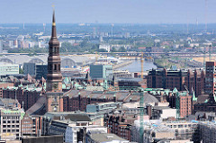 Kirchturm der St. Katharinenkirche, dahinter die historischen Lagergebäude der Hamburger Speicherstadt - in der Bildmitte der Oberhafenkanal und die Gemüsehallen in Hamburg Hammerbrook.